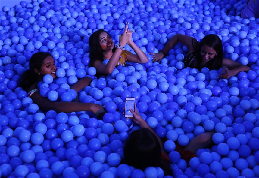 Friends enjoy a ball pit and pose for a photo together.